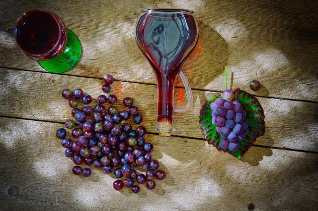 photo of wine bottle on table with grapes and wine glass